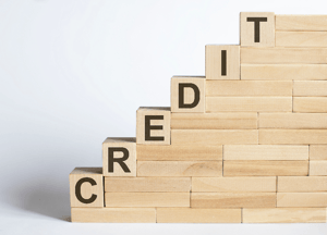 Wooden building blocks forming an incline like a staircase, with the end blocks spelling out "CREDIT", representing building credit after bankruptcy in MN.
