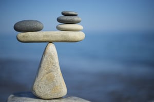 A scale made out of rocks, creating a balanced and serene scene with the ocean in the background, raising the question, Should I file Chapter 7 or Chapter 13 in Minnesota?