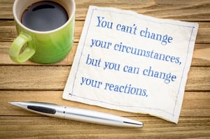 A green coffee cup, pen and note that reads "You can't change your circumstances, but you can change your reactions.", referring to being embarrassed to file bankruptcy.