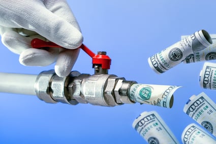 A gloved white hand on the left side of the screen twists a red lever on a silver spigot dispensing rolled up $100 bills, of which there are five against a blue background posing the question, How can disposable income impact my MN Bankruptcy case?