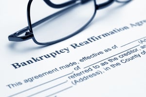 Closeup of a bankruptcy reaffirmation agreement in Minnesota form, with black-rimmed glasses sitting on the form.