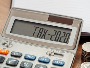 A small calculator with "TAX-2020" displayed on the screen, sitting on a wooden desk, posing the question, Are there tax ramifications of filing bankruptcy in Minnesota?