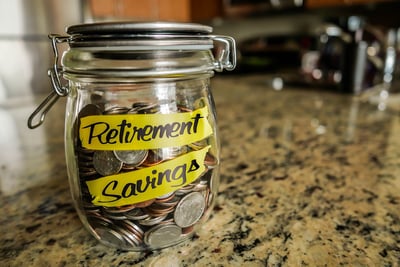 A clear glass jar with a hinged lid, filled with coins, on top of a marbled countertop poses the question, What happens to my retirement accounts during bankruptcy in Minnesota?