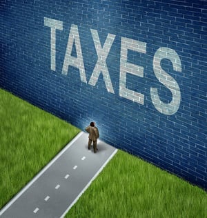 Rendering of a small man on an asphault road with green grass on the other side that ends at a tall, foreboding, blue brick wall with "TAXES" in white lettering, posing the question, What happens to my taxes in a Chapter 13 bankruptcy in Minnesota?