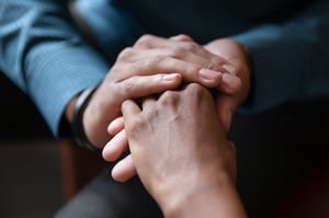 Closeup of a pair of hands gently clasping the hand of another person who is scared and uncertain, symbolizing the dedication of the lawyers at Kain & Scott to make sure you do not feel alone when filing bankruptcy in MN.