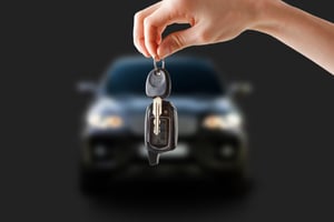 A hand holding keys in focus in the foreground, with a black car blurred in the background, asking the question, What are non-exempt assets in Chapter 7 Bankruptcy?
