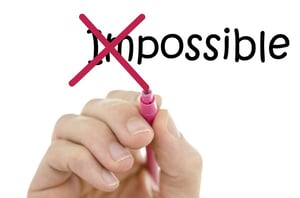 A hand holding a red marker, crossing out the "im" in the word "impossible" that is written, to reveal the word "possible" to represent life after bankruptcy Chapter 13 in Duluth, MN.