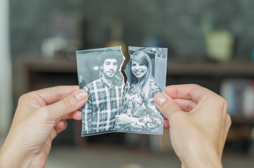 Two hands holding a torn black and white picture of a young couple, representing how bankruptcy can set you free from co-signed debts with your ex.
