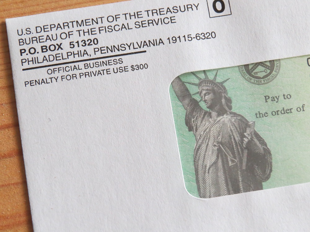Closeup of a slightly askew Economic Impact Payment, the Statue of Liberty against a light green background visible through the window of a white envelope displaying the return address of the U.S. Department of The Treasury, asking the question, Can s bankruptcy trustee take my recovery rebate credit in Minnesota?
