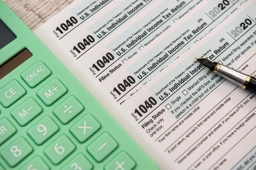 Closeup of a mint green colored calculator placed on top of tax forms, raising the question, How does filing chapter bankruptcy affect filing taxes in Minnesota?