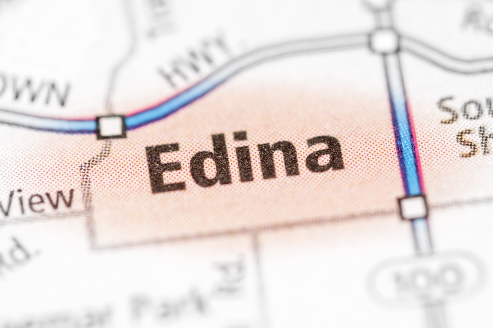 Closeup of a paper map focused on Edina, Minnesota. Edina is colored in a peach color, with Highway 62 and 100 highlighted in blue, asking the question, Are you searching for a chapter 7 bankruptcy lawyer near Edina, MN?