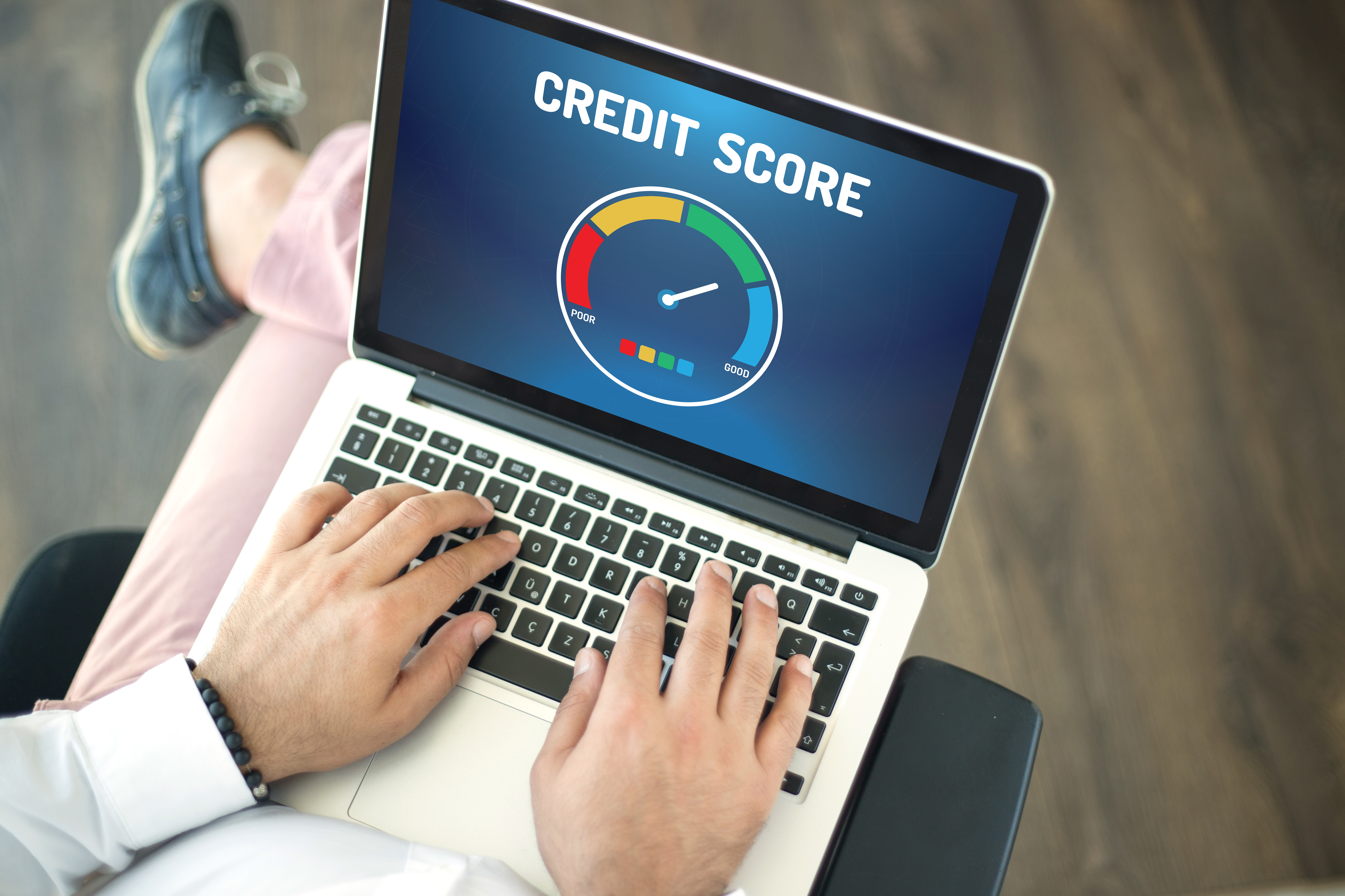 A man's hands typing on a laptop, with the screen displaying an image of a credit score scale, title CREDIT SCORE, posing the question, What does bankruptcy do to my credit in Minnesota?