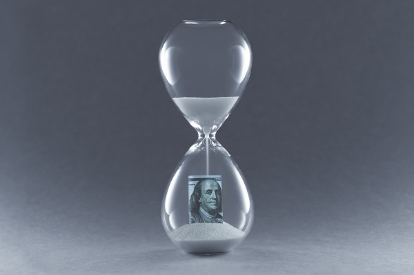 A rounded hourglass with white sand running from the top into the bottom onto a rolled up $100 bill. The hourglass sits against a a gradient grey background, posing the question, When can I file bankruptcy again in Minnesota?